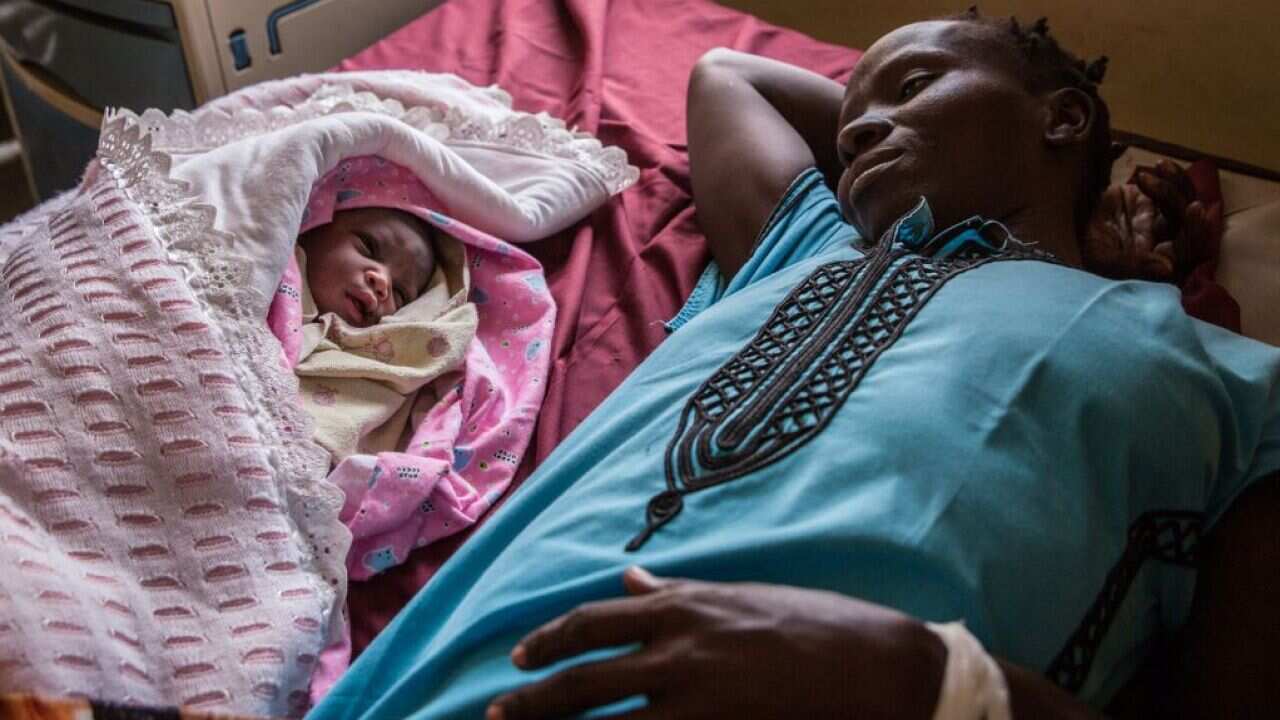 a mother lying down with her newborn after its delivery at the Juba Teaching Hospital in Juba, the South Sudanese capital's only fully functioning maternity ward which has five beds and only solar-powered electricity. 