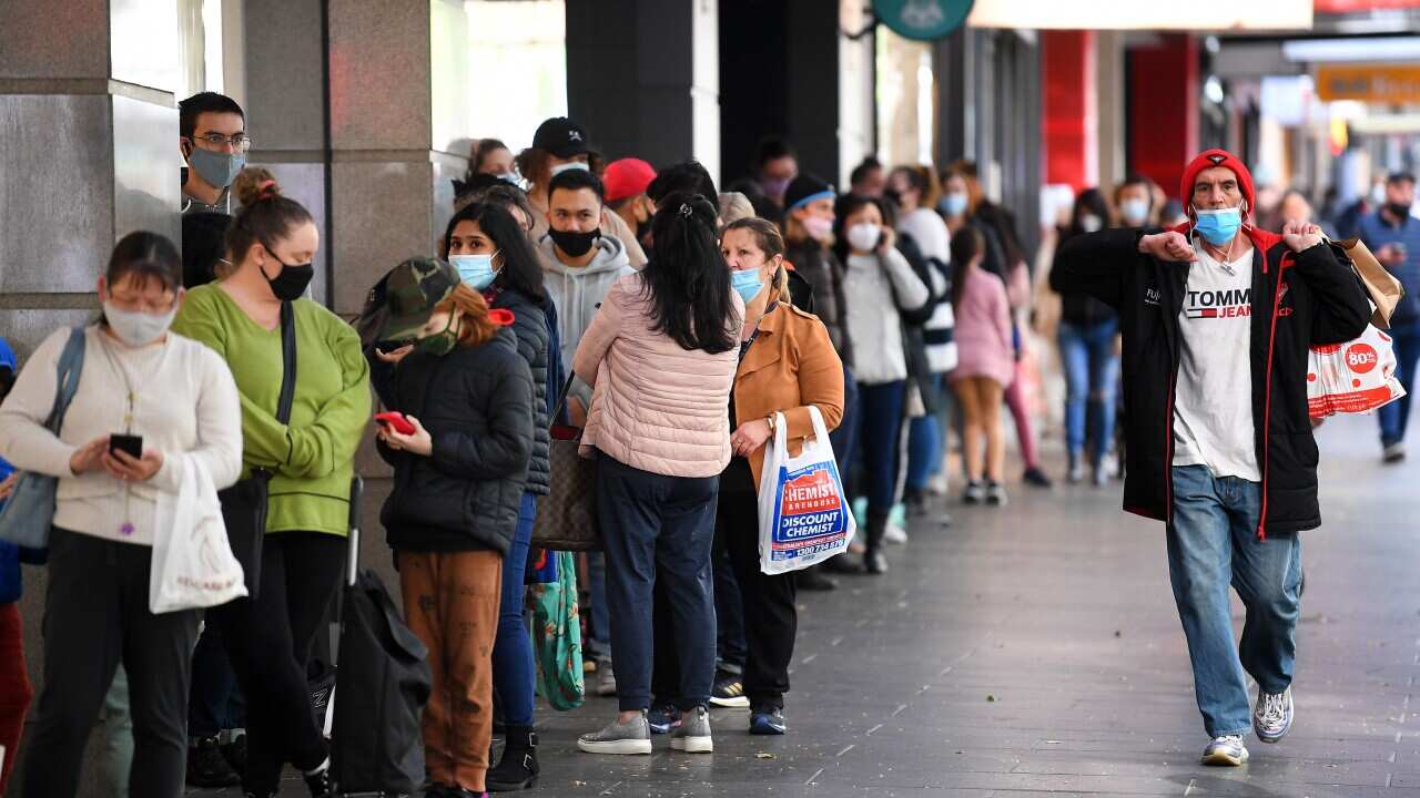 People are seen lining up outside of a retail store in Melbourne, Friday, October 29, 2021. At 6pm, the border between Melbourne and the regions will come down, masks will no longer need to be worn outdoors, indoor entertainment venues, gyms and retail ca