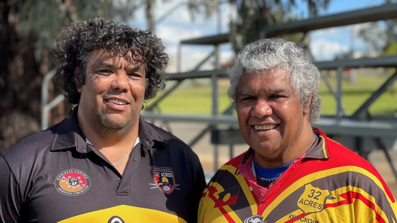 All Blacks coach Phil Ingram standing side by side with his father Steve, both wearing colourful yellow and brown Koori Knockout shirts of their team the Wiradjuri Erambie All Blacks.