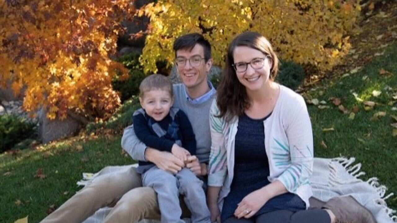 Man, woman, and young boy sitting on grass under trees