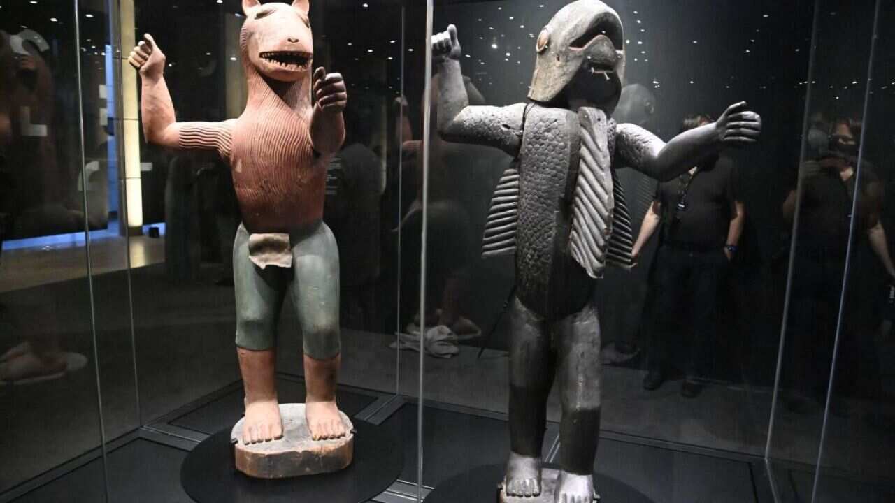 People look at anthropo-zoomorphic statues depicting King Glele (L)and King Behanzin (R) during an exhibition of returned looted Benin artefacts.