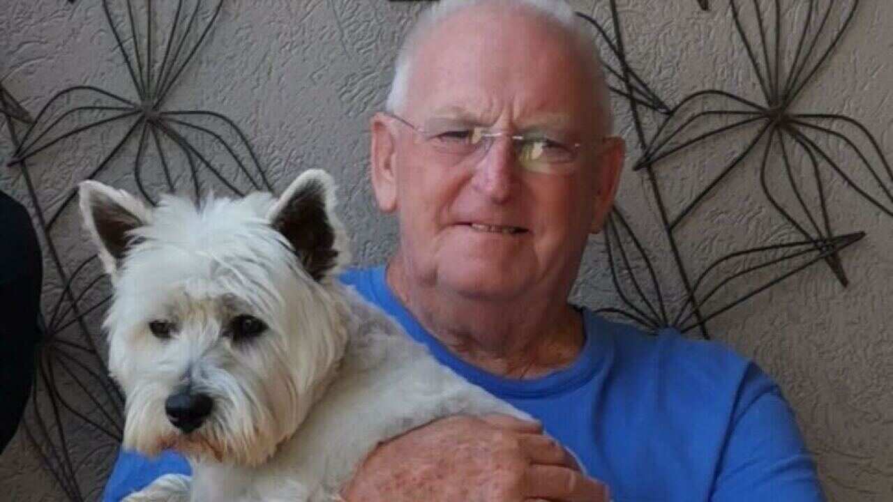 an older man wearing a blue shirt holding a white dog