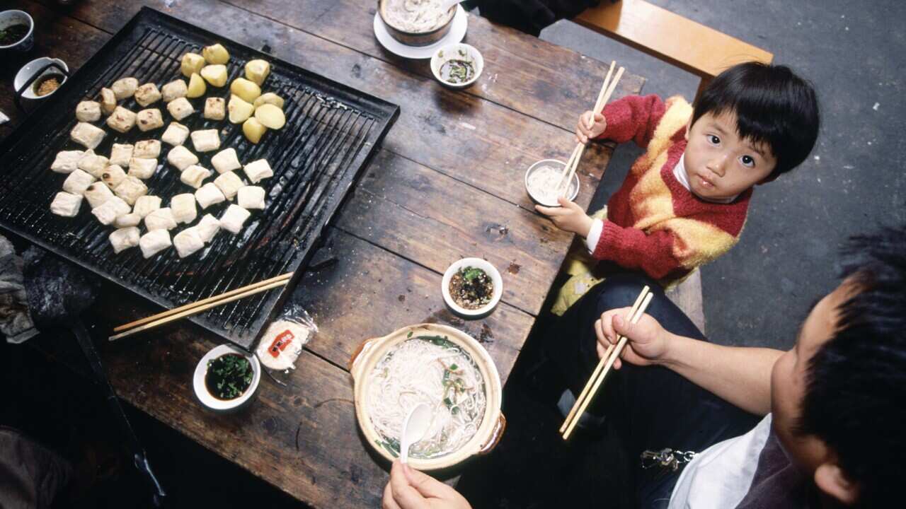 Father and child eating noodle and tofu in street