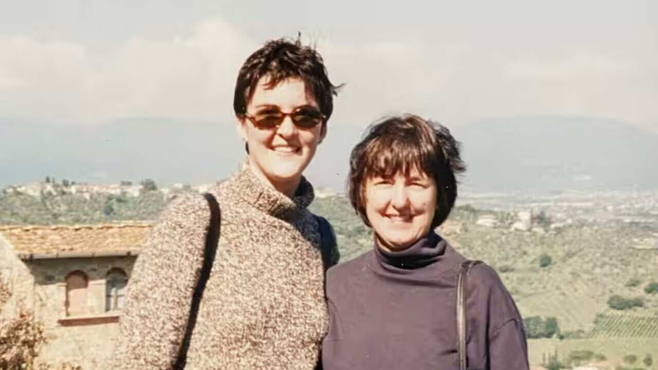 Two women stand side by side and smile at the camera.