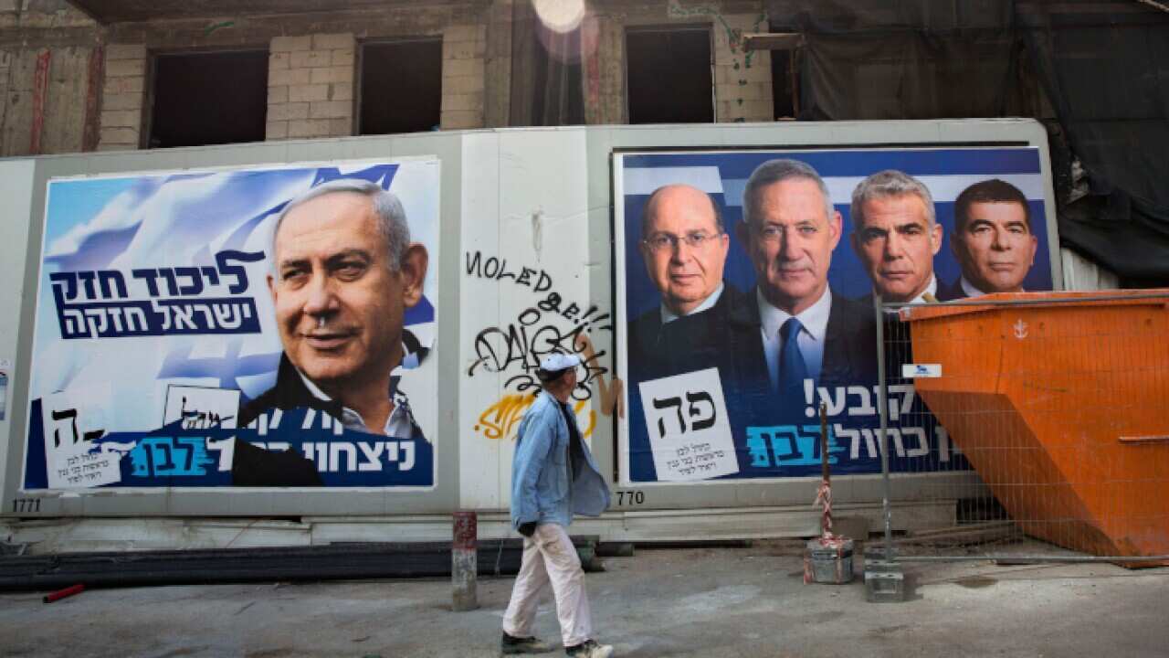 A man walks by election campaign billboards showing Israeli Prime Minister and head of the Likud party Benjamin Netanyahu, left, alongside the Blue and White party leaders