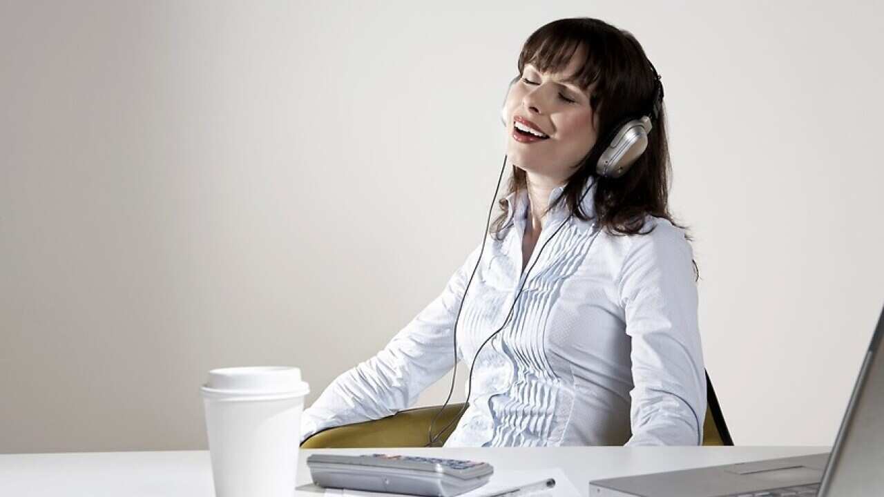 Smiling woman with earphones relaxing at desk