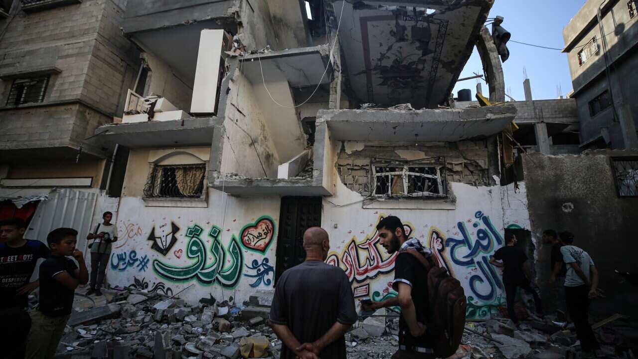 A group of people standing outside a badly damaged building.