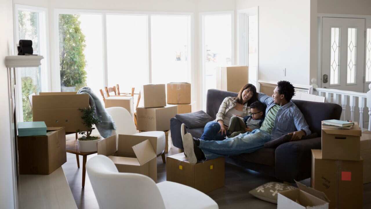 Moving boxes surrounding family relaxing on sofa