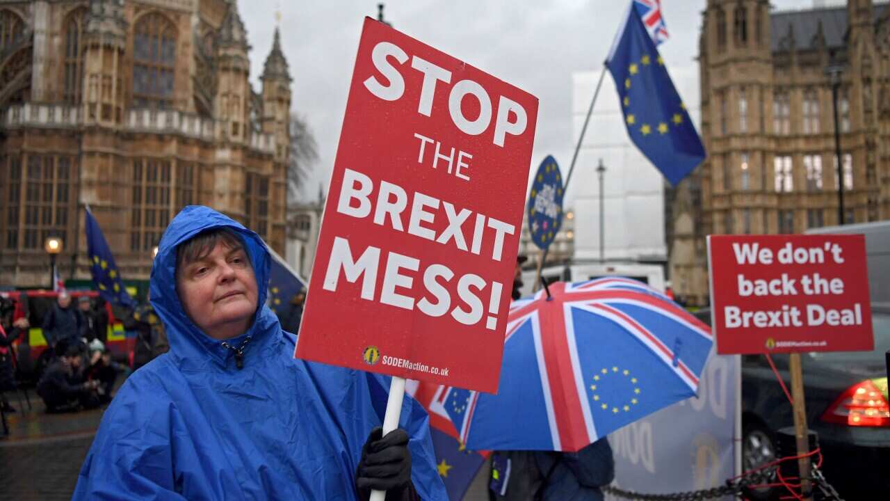Brexit protesters shelter from a rain shower while Prime Minister Theresa May faces a no confidence vote in parliament.