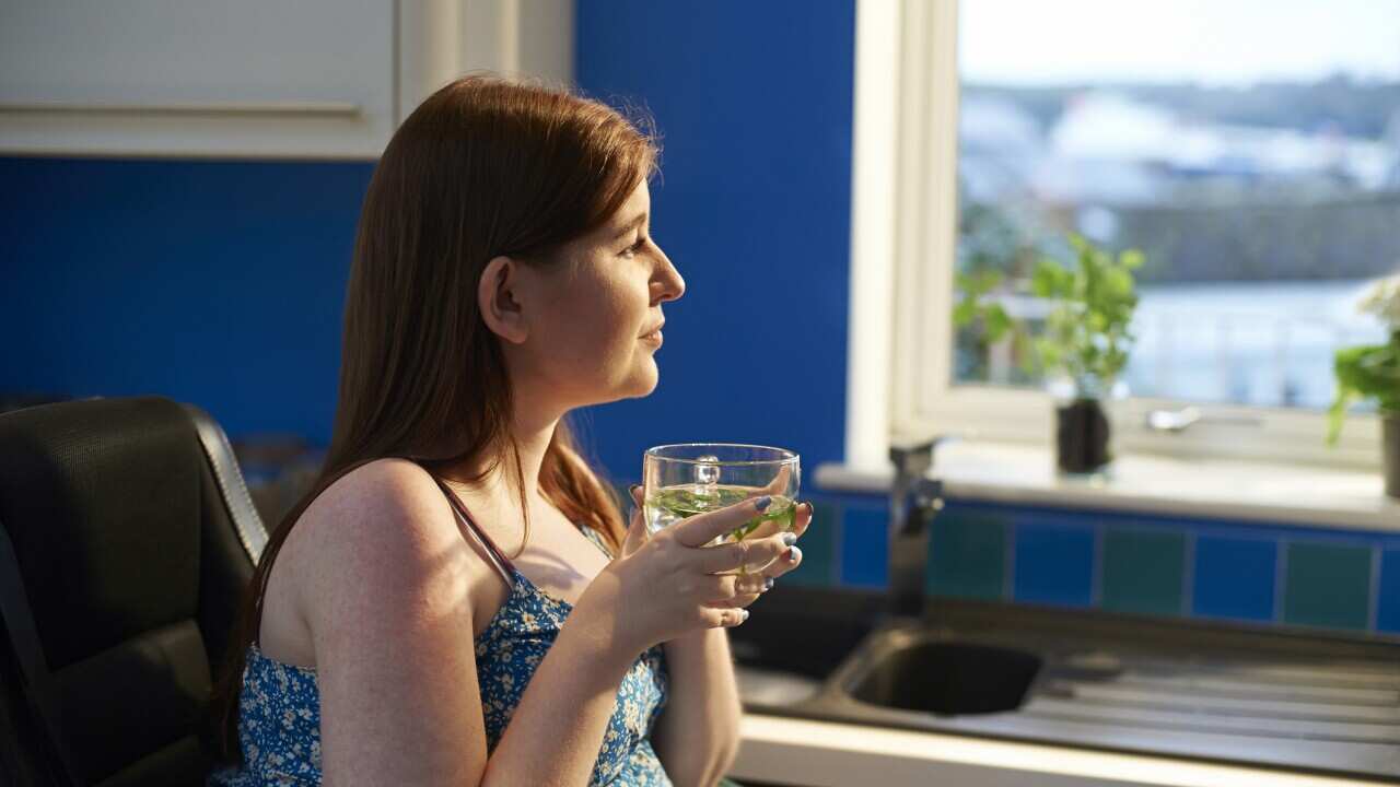 Woman looking out of kitchen with fresh mint tea.