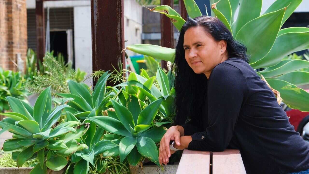 Henrietta Baird standing in front of garden bed. 