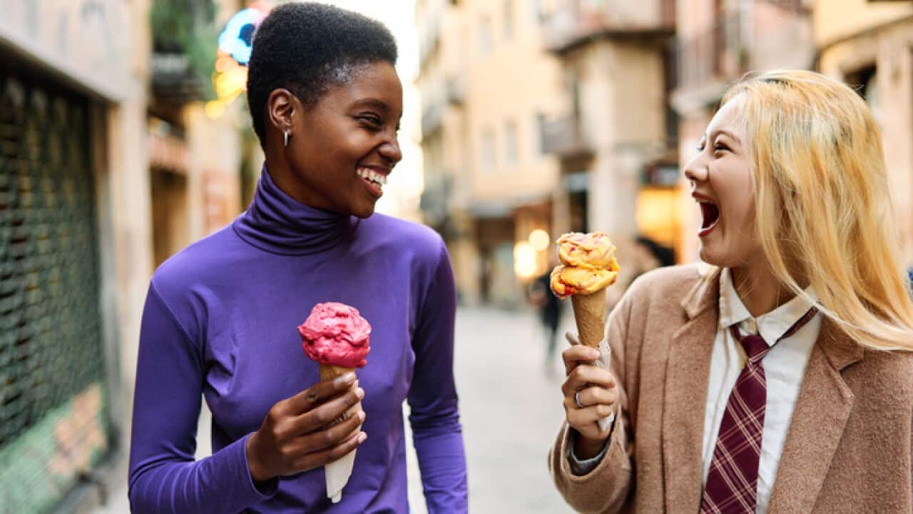 Two female friends on a street eating ice cream