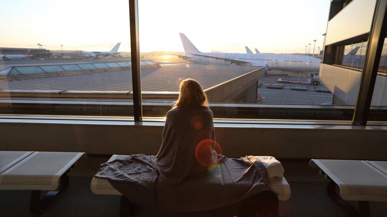 Woman relaxes in airport lobby, planes in distance