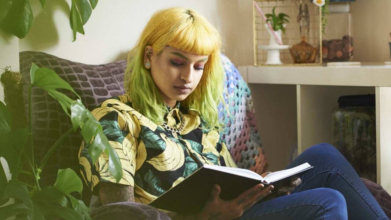 Young hipster woman reading a book in her living room