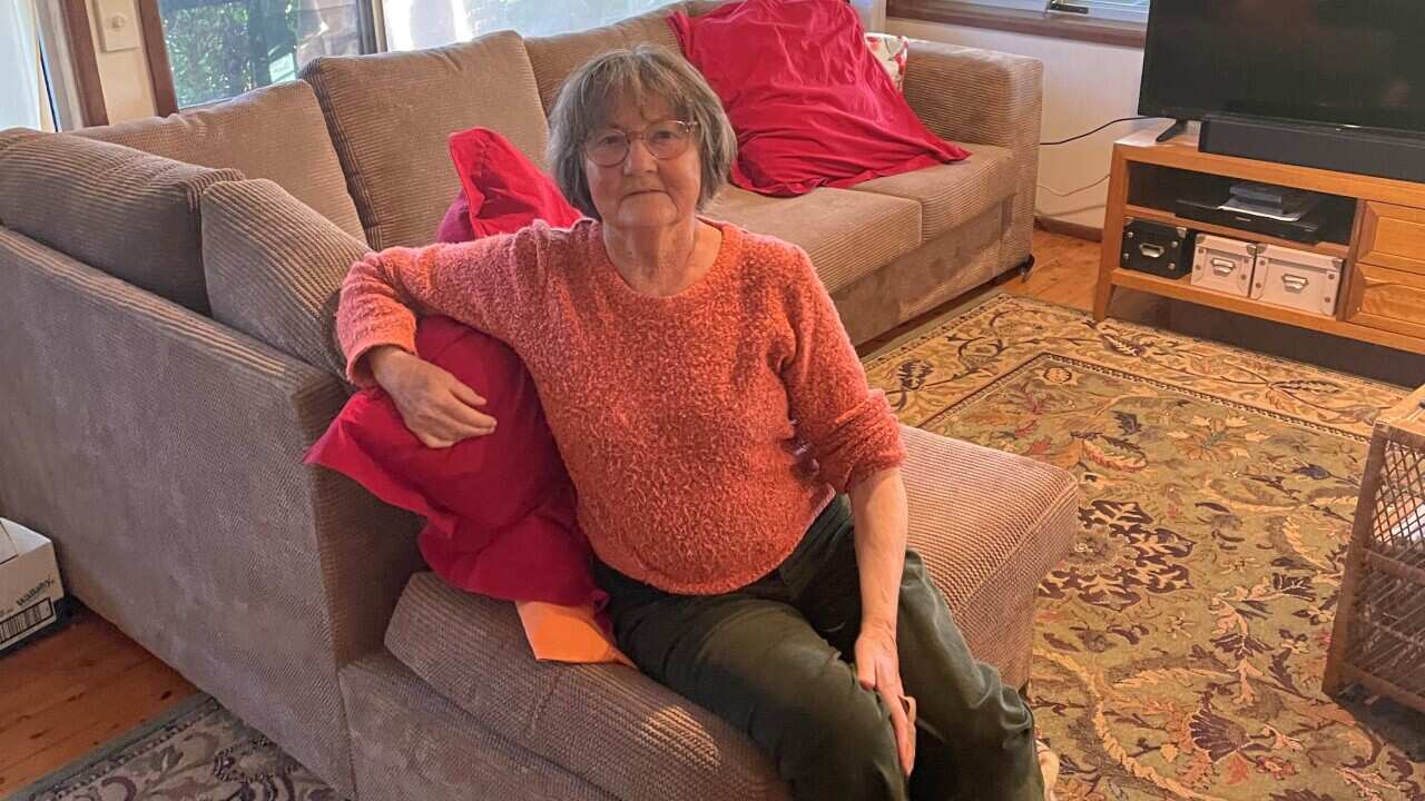 A senior lady sitting on a couch in her lounge room.