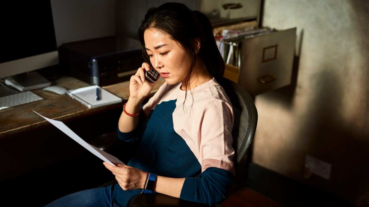 Serious Asian woman sitting in office chair concerned 