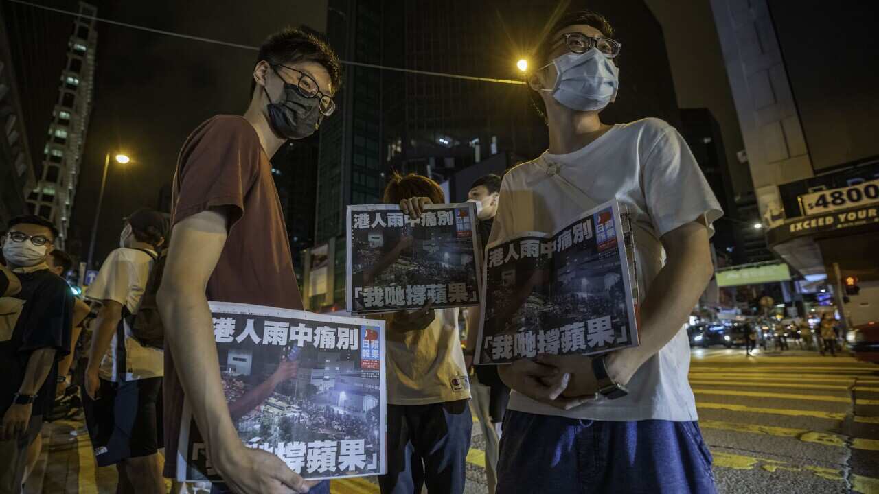 Supporters hold copies of the final edition of the Apply Daily newspaper early on 24 June.