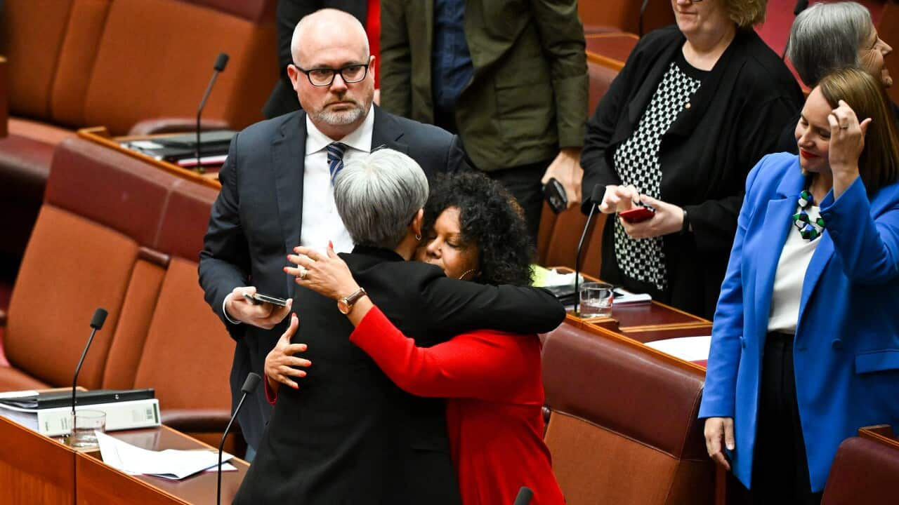 Two women embrace each other in parliament house.