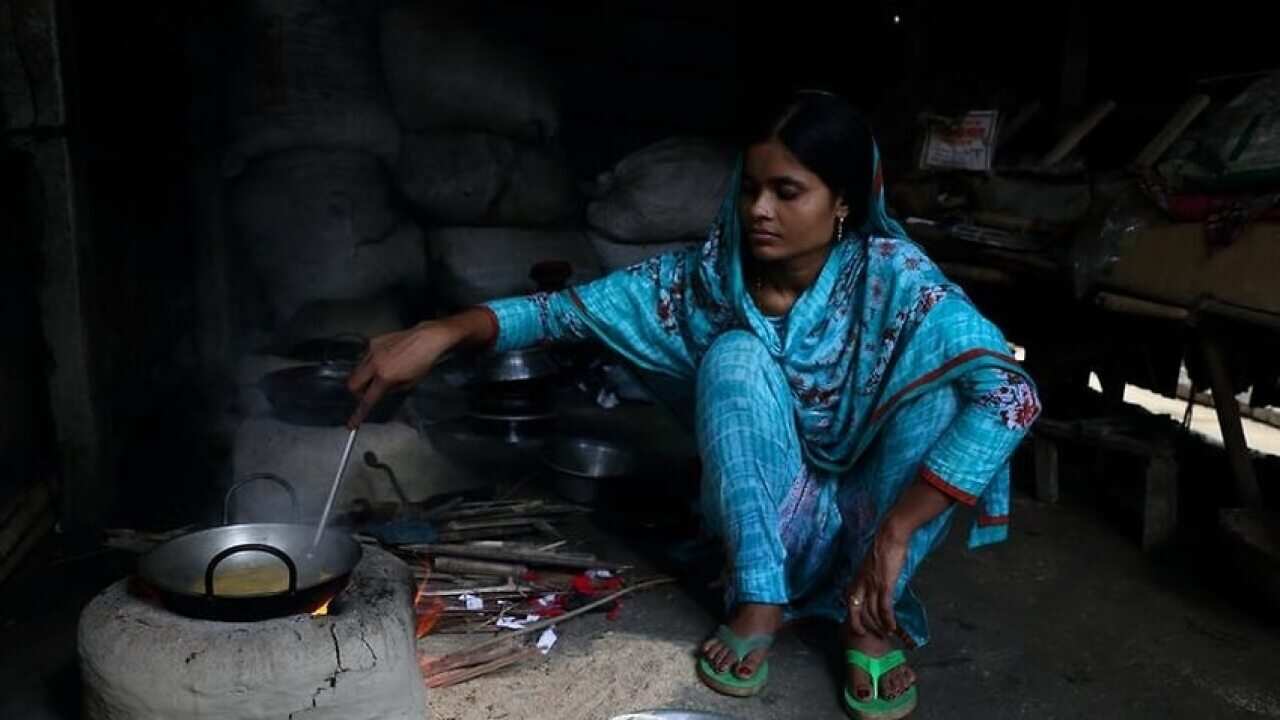 Image of a female Bangladeshi factory worker cooking at her home