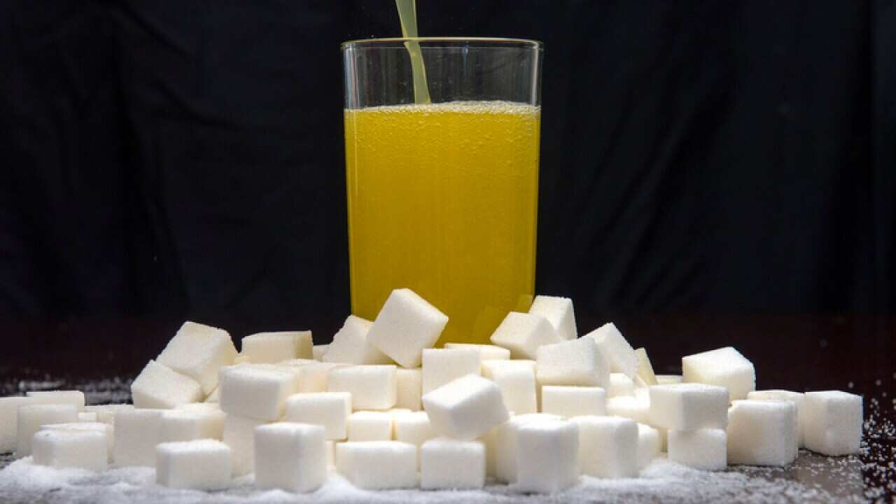 An orange carbonated drink surrounded by sugar cubes