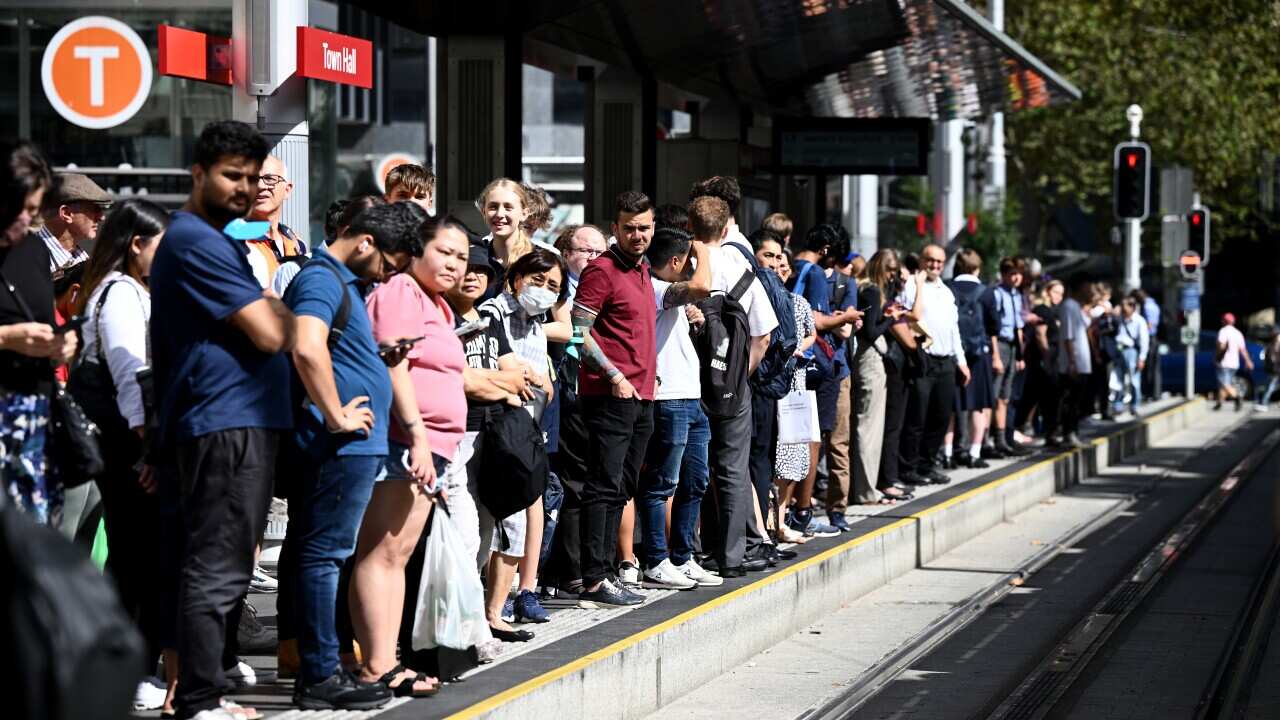 Commuters wait for light rail services standing on a platform