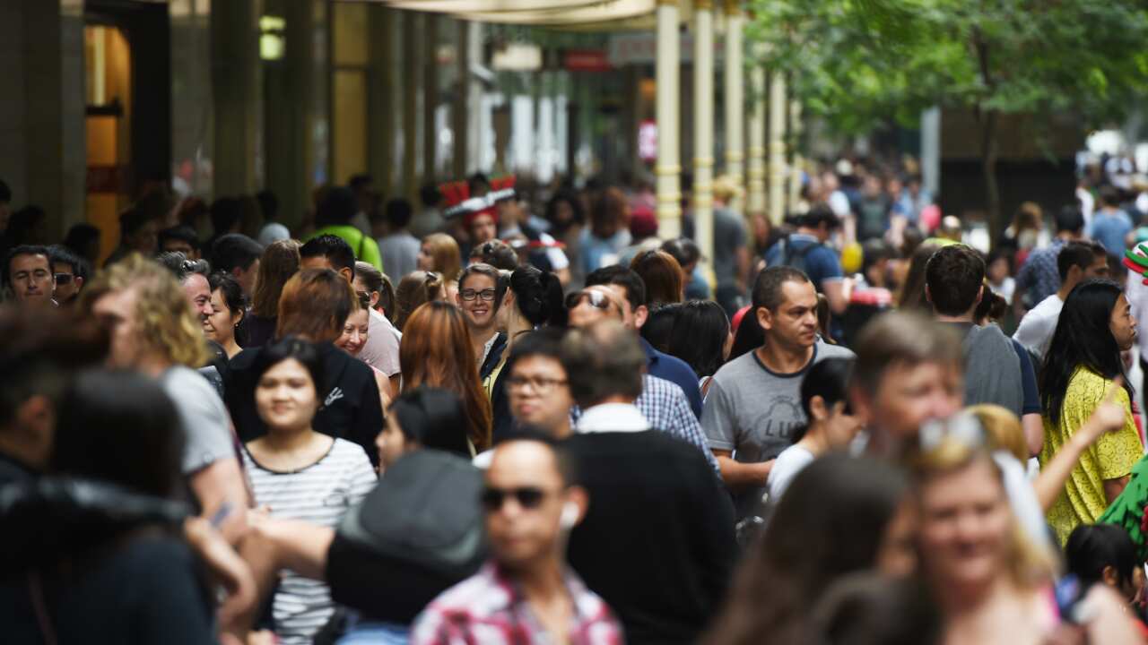 Una gran multitud de personas moviéndose por un centro comercial al aire libre.